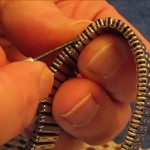 Removing_link_stretch_type_metal_watch_band_with_jeweler's_screwdriver